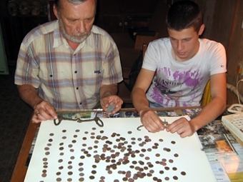 Сотрудники демонстрируют найденные монеты. Фото с сайта .Восточноукраинского национального университета