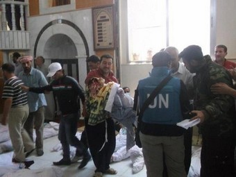 Наблюдатели ООН осматривают тела погибших в Хуле. Фото ©AFP/HO/SHAAM NEWS NETWORK